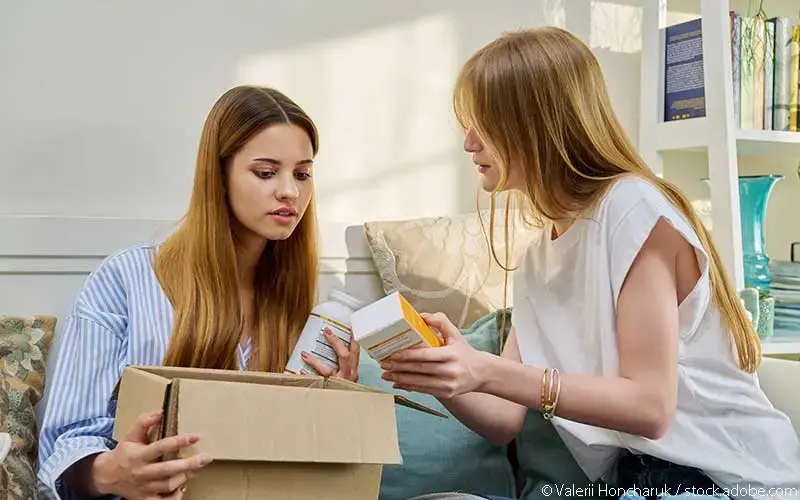 Zwei Frauen packen Interneteinkaeufe aus